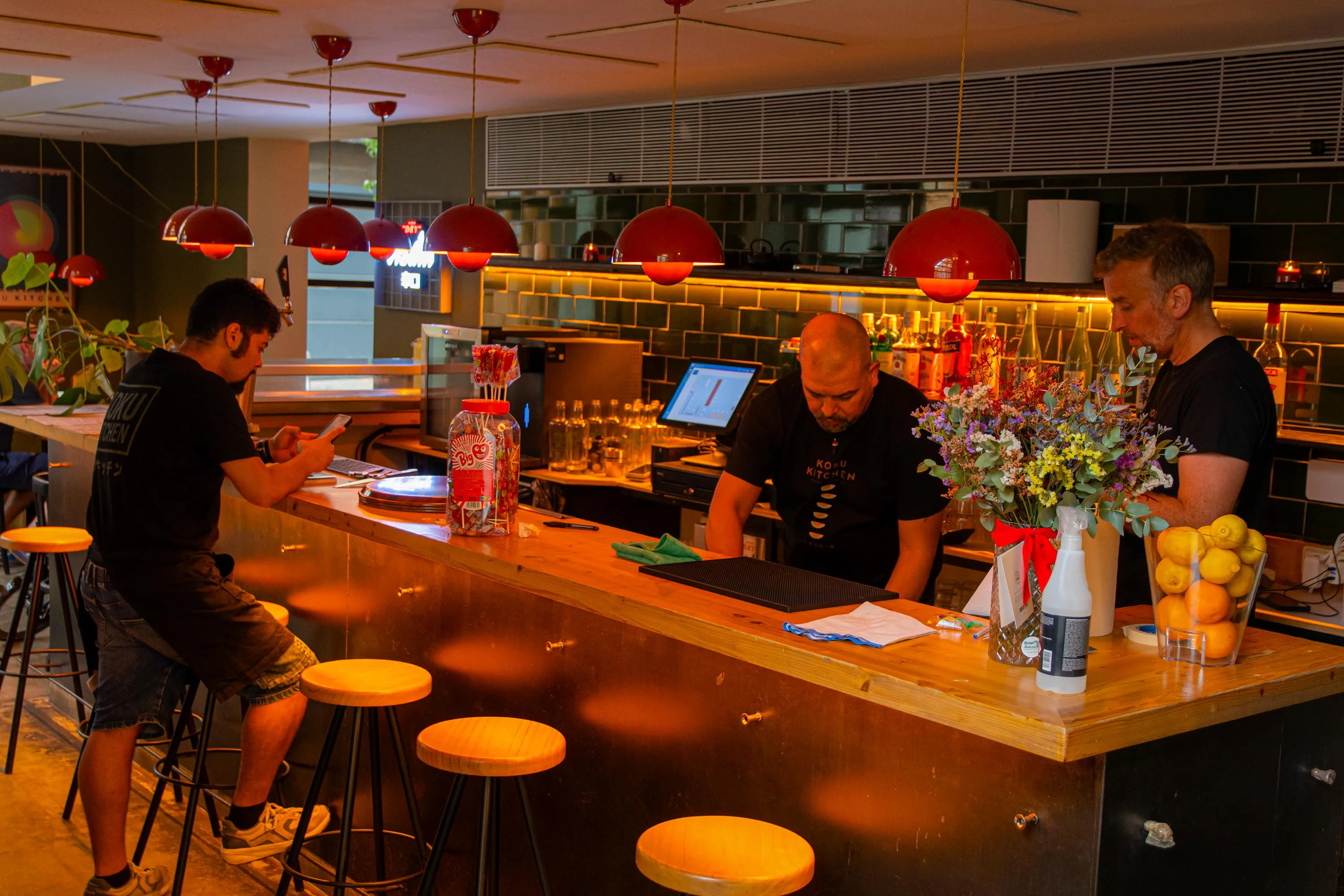 The team at the bar of Koku Kitchen Gràcia, with flowers and lemons on the counter