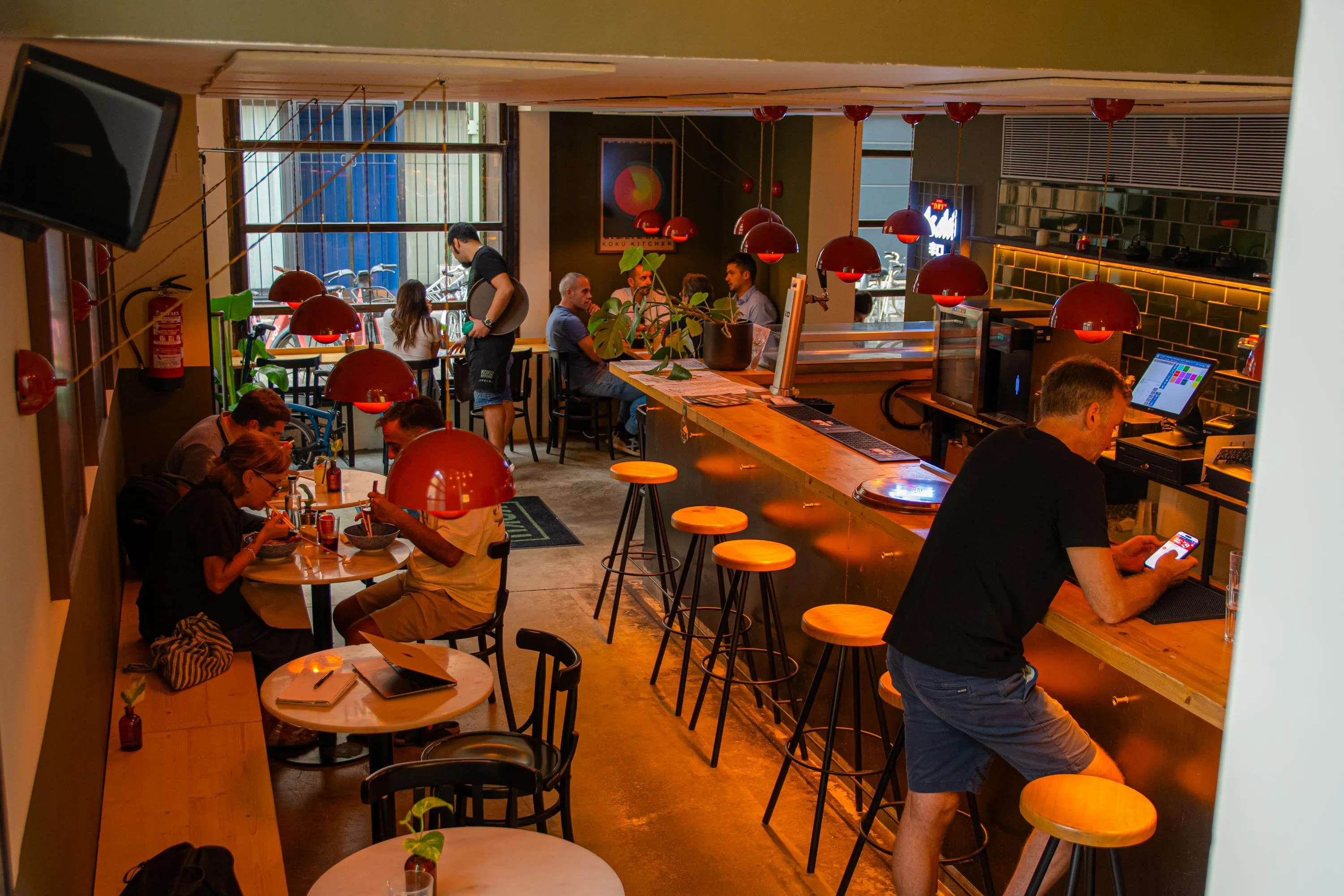 The dining room and the bar of Koku Kitchen Gràcia seen from above, with the windows onto the street at the far end