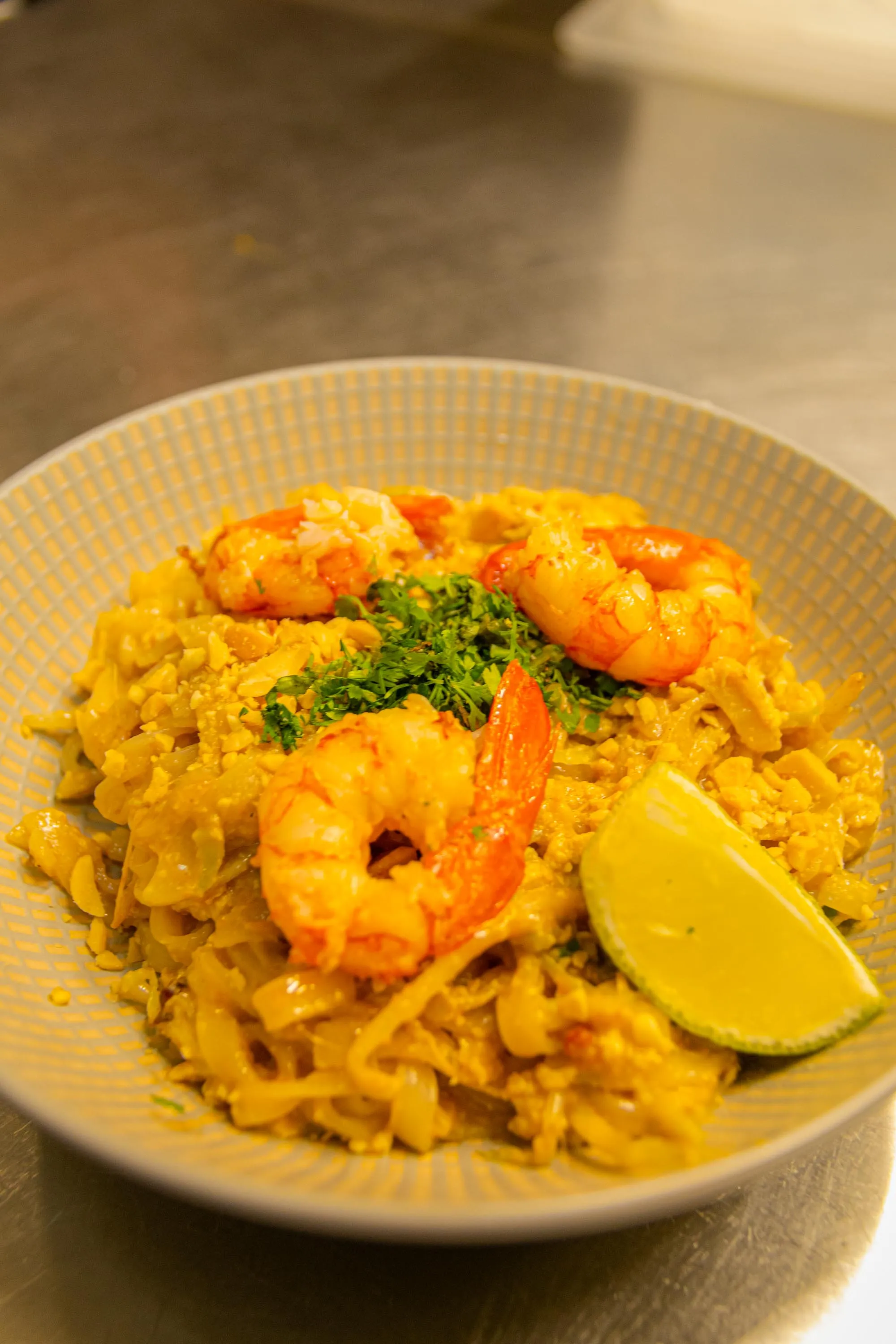 A plate of pad thai with prawns, peanuts and a wedge of lime at Koku Kitchen Gràcia